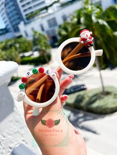 a person holding up some kind of sunglasses with stickers on the lens and an image of santa claus behind it