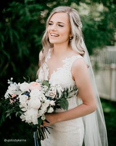 a woman in a wedding dress holding a bouquet and smiling at the camera while standing outside