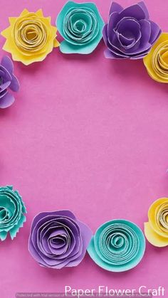 paper flowers arranged in a circle on a pink background