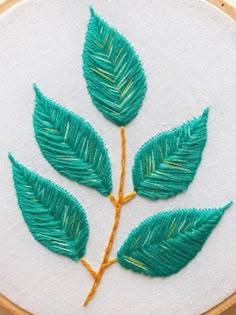 a close up of a embroidery on a piece of cloth with leaves in the middle