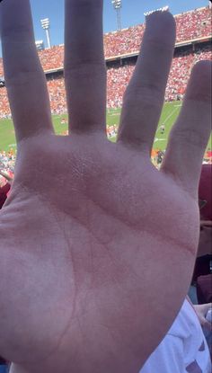 a hand is held up in front of a football stadium