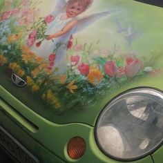 a green car with an angel painted on it's side and flowers in the front