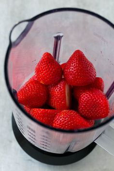 a blender filled with strawberries on top of a table