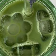 a green drink with ice cubes in it