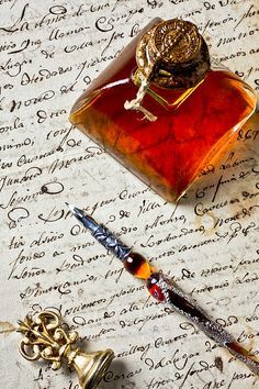 a bottle of ink with a snail on it sitting next to a pen and writing utensils