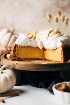 a slice of pumpkin cheesecake on a plate with whipped cream and pumpkins in the background