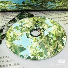 the dvd is sitting on top of an open book and it's contents are covered in green leaves