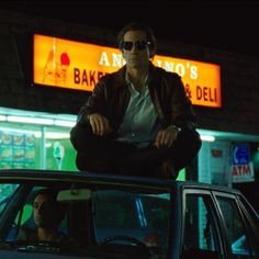 a man sitting on the hood of a car in front of a baker's