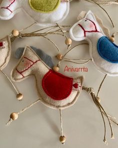 four felt bird ornaments hanging from twine with string and wood bead around them