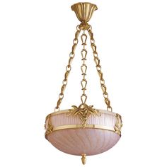 a chandelier hanging from the ceiling with gold chains and pink glass shades on it