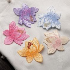 four different colored flowers sitting on top of a white cloth