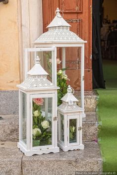 two white lanterns with flowers in them sitting on the steps