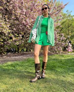 a woman standing in the grass with her legs crossed