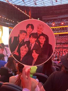 a fan holds up a photo of the cast of btob in front of an audience