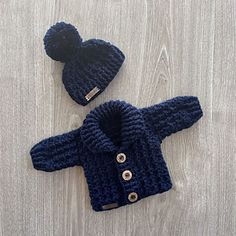 two knitted sweaters and a hat on a wooden surface