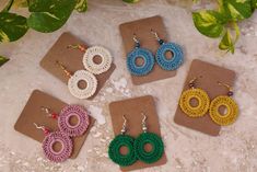 four pairs of crochet earrings are displayed on a table next to each other