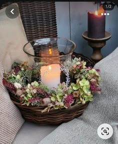 a wicker basket filled with flowers and a lit candle sitting on top of it