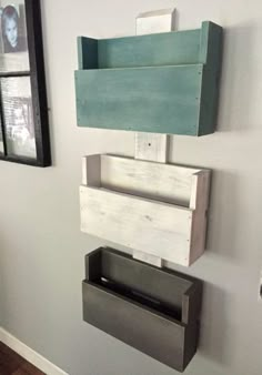 three wooden boxes are stacked on top of each other in front of a white wall