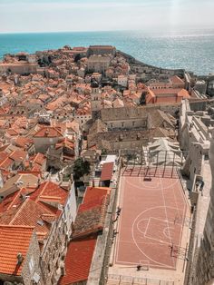 an aerial view of a basketball court in the middle of a city by the ocean