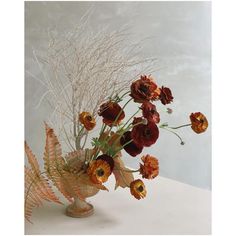 a vase filled with lots of flowers on top of a white table next to a wall