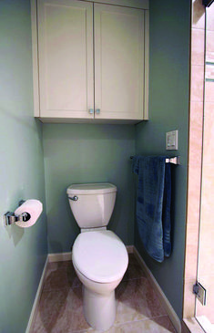 a white toilet sitting inside of a bathroom next to a wall mounted cabinet and towel dispenser