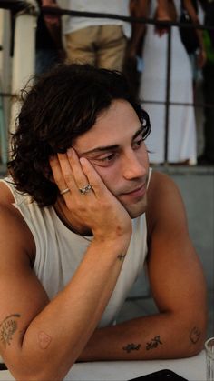 a man sitting at a table with his hand on his face and looking off to the side