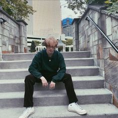 a young man sitting on steps in front of some buildings