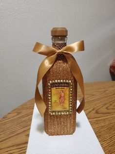 a bottle that is sitting on top of a white paper with a gold ribbon around it