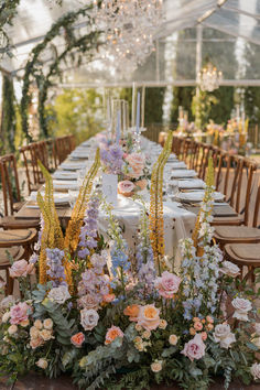 a long table with flowers and greenery is set up for an outdoor wedding reception