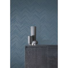 two vases on top of a dresser against a blue wall