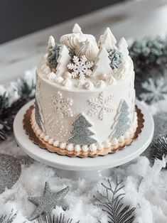 a decorated cake sitting on top of a white plate covered in frosting and pine trees