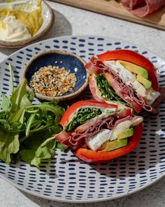 a white plate topped with two sandwiches and veggies on top of a table