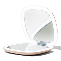 an empty compact mirror sitting on top of a white surface with its reflection in it