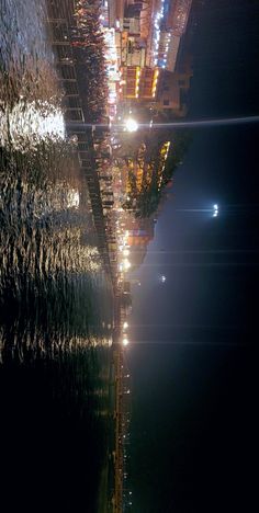 an aerial view of the city lights at night from across the water with reflections in the water