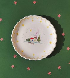 a white plate with a house on it and stars around the edge, against a green background