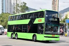 a green double decker bus driving down the street