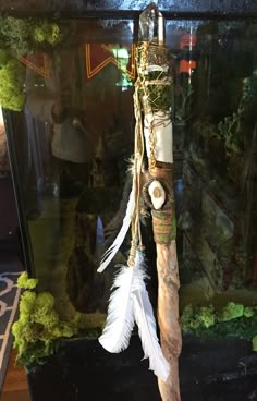 a wooden stick with feathers hanging from it's side in front of a glass case