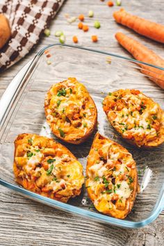 four baked sweet potatoes in a glass dish next to carrots