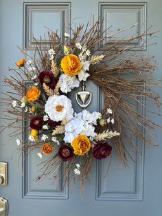 a wreath is hanging on the front door with flowers and grasses in it, as well as an antlers