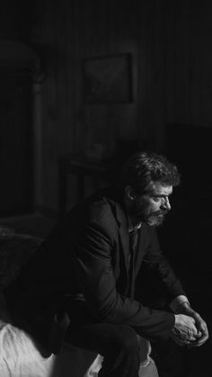 a man sitting on top of a bed in a dark room