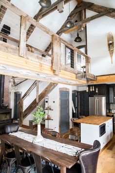 an open kitchen and dining room area with exposed wood beams on the ceiling, along with modern appliances