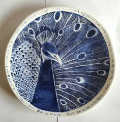 a blue and white plate with a large peacock on it's side, in front of a wall