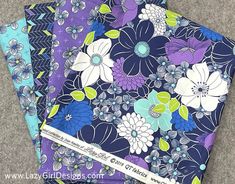 three pieces of purple, blue and green fabric with flowers on them are folded together