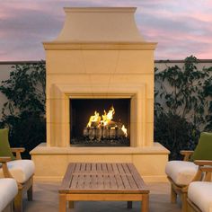 a fire place sitting on top of a patio next to two chairs and a table