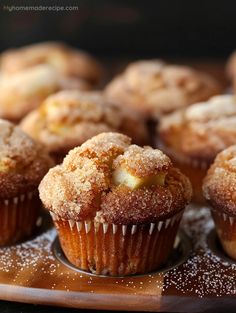 some sugary muffins are sitting on a wooden plate with powdered sugar