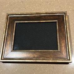 a wooden frame with a black board in the middle on a counter top next to a brown wall