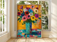 a vase filled with lots of colorful flowers on top of a wooden floor next to an open window