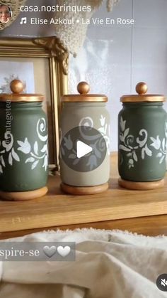 three green canisters sitting on top of a wooden shelf next to a mirror