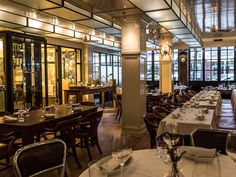 an empty restaurant with many tables and chairs set up for formal dining, including wine glasses on the table