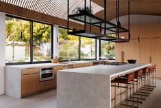 a kitchen with an island and lots of counter space next to large windows that look out onto the backyard